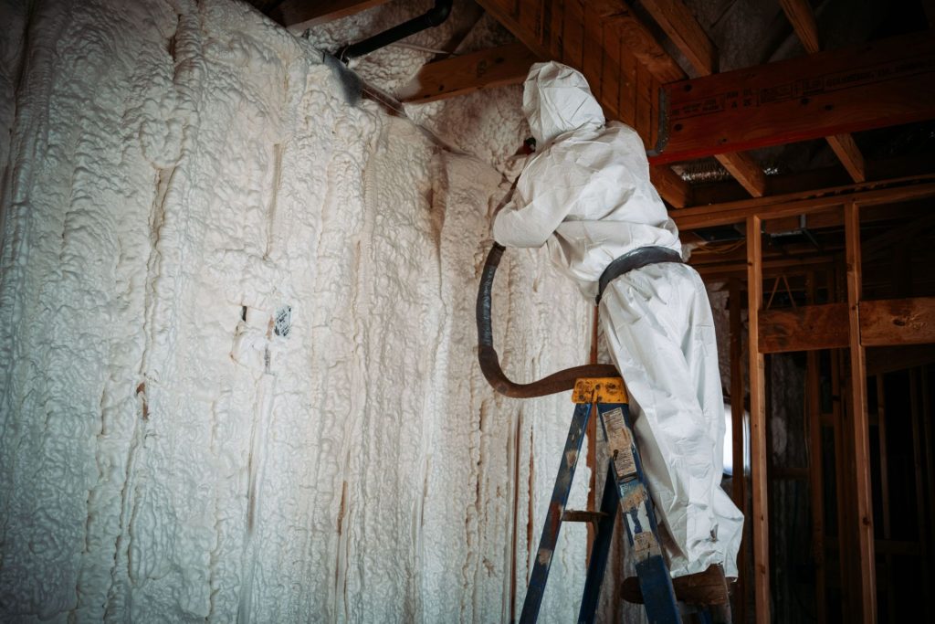man in white protective suit spraying foam insulation