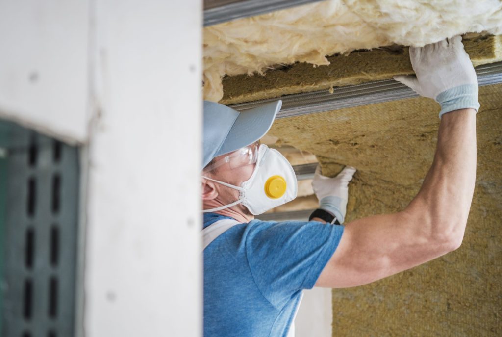 man wearing a cap and mask fixing the insulation