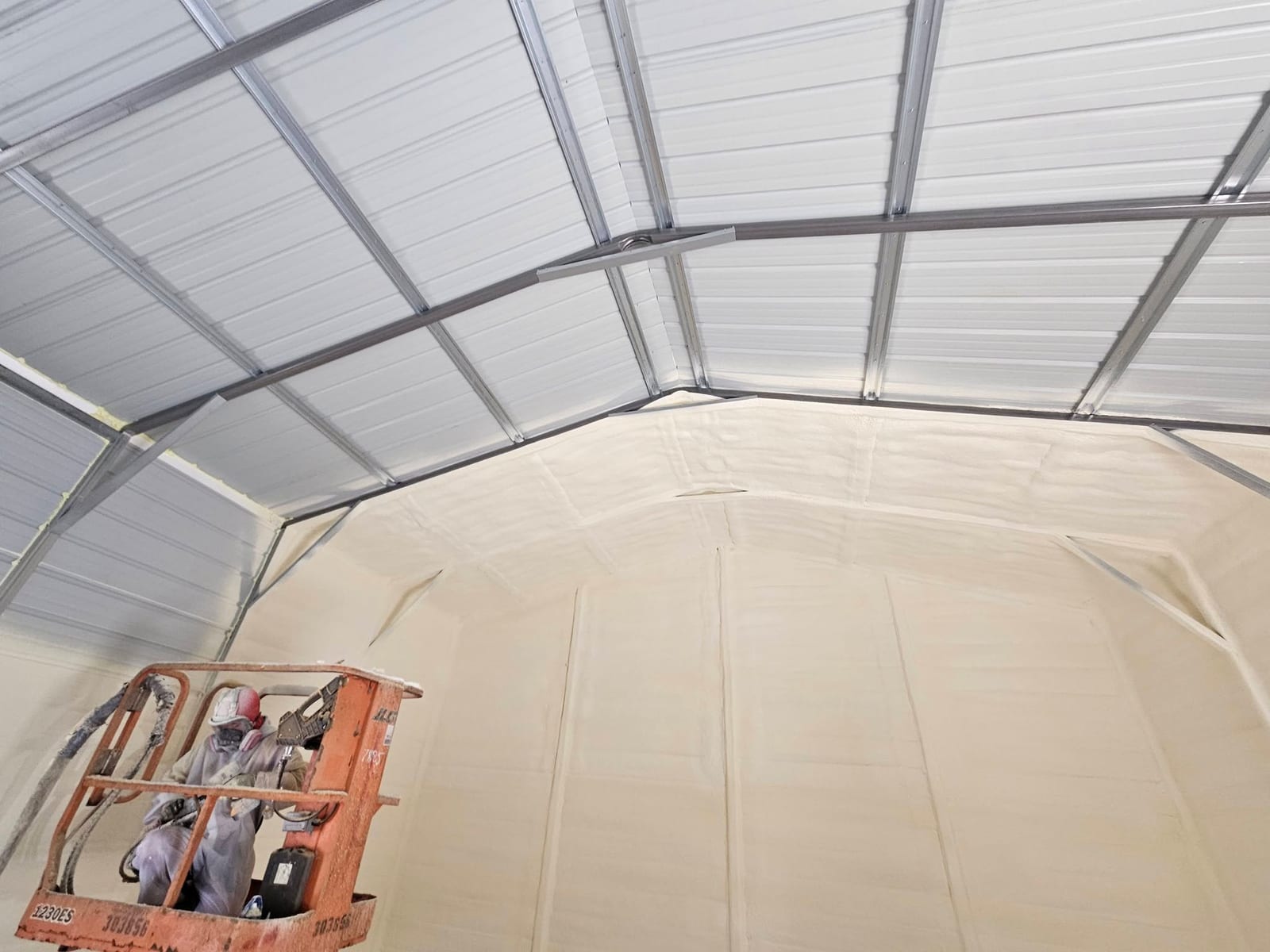 Metal garage with closed-cell spray foam sprayed between the steel ceiling purlins