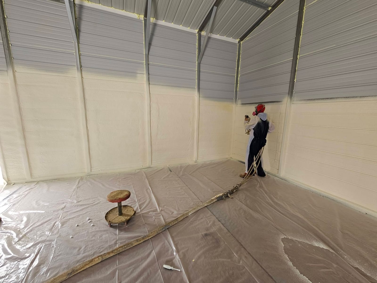 Installer spraying foam insulation on a metal shop wall