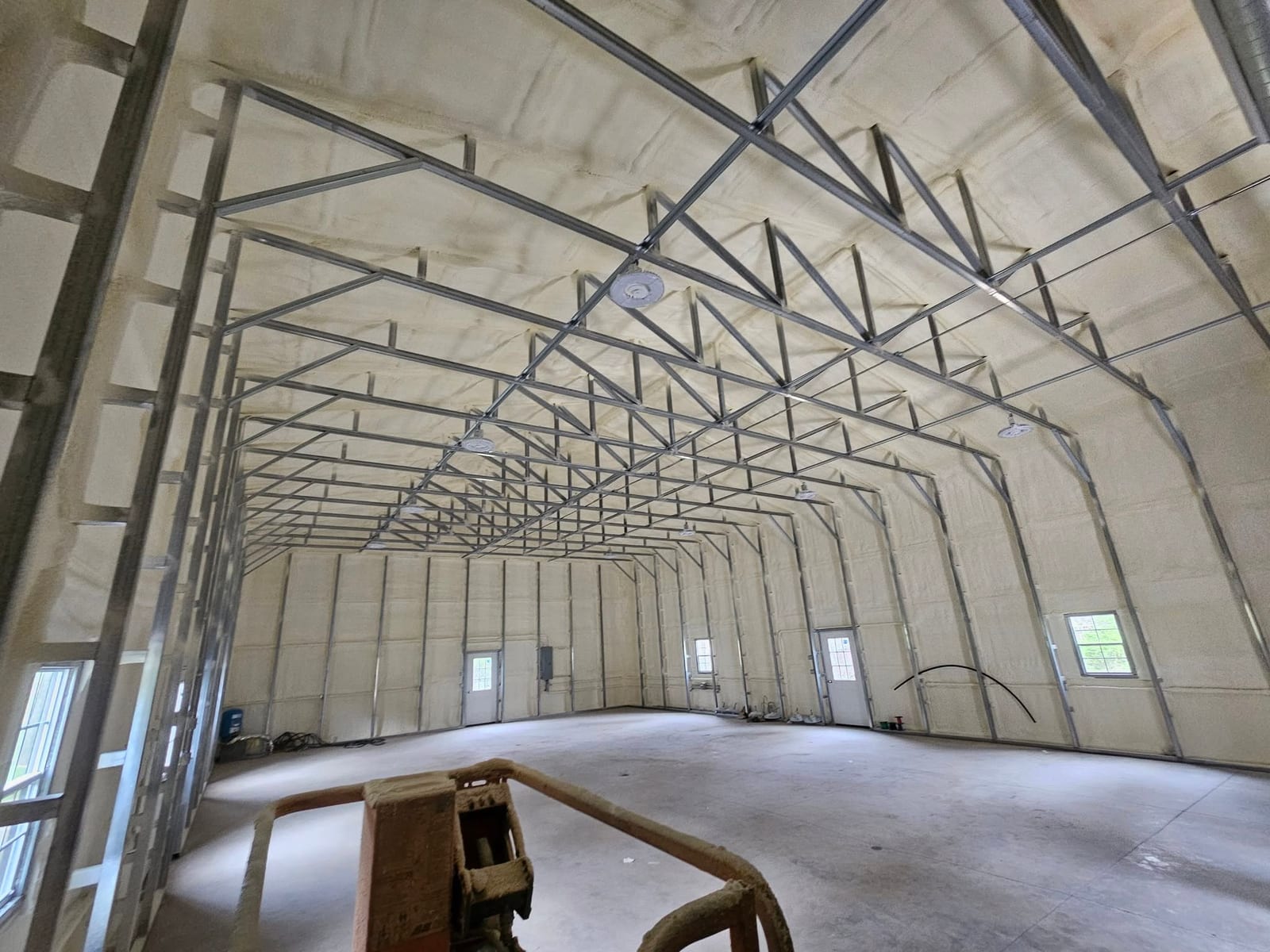 Large metal building interior during spray foam insulation