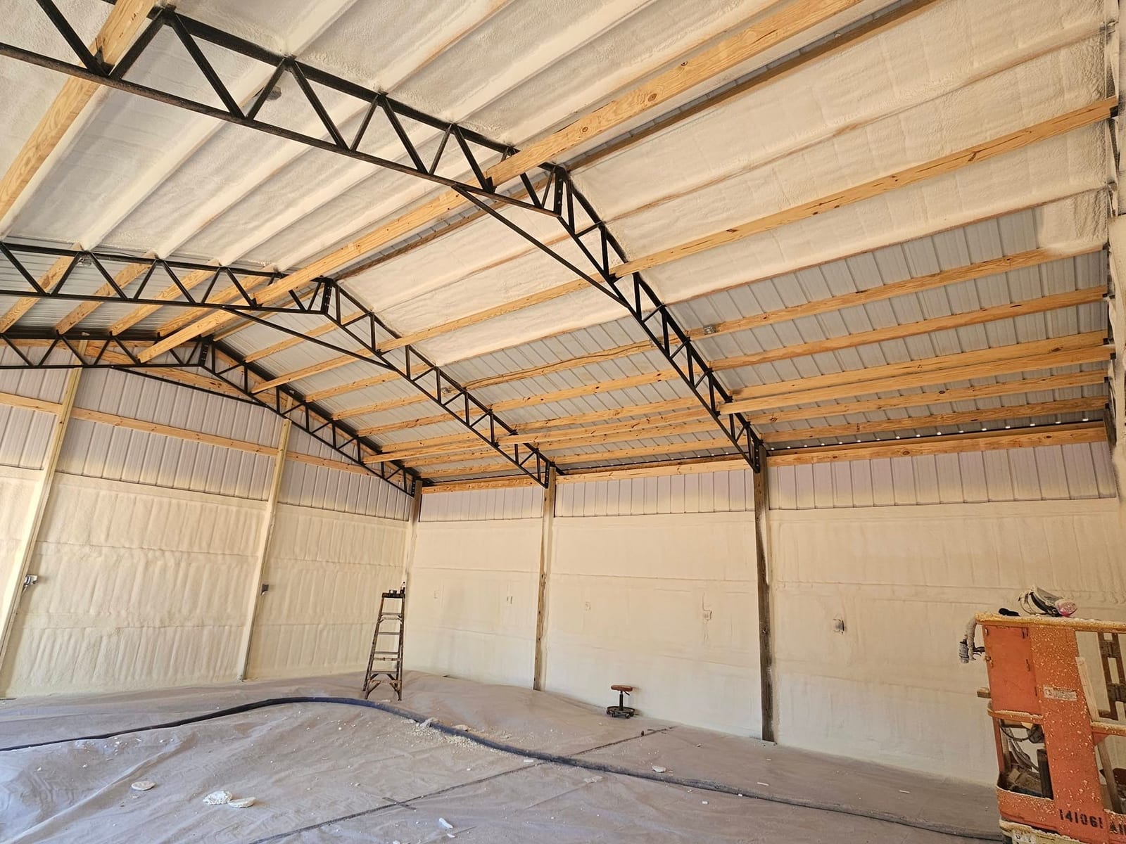 Pole barn roof insulated with spray foam above steel trusses